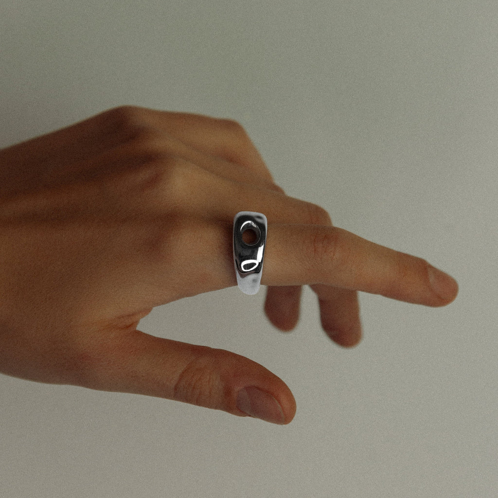 Hand with a silver ring on a plain background
