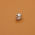A silver ring with a small spherical bead on top, photographed on a solid warm brown background.