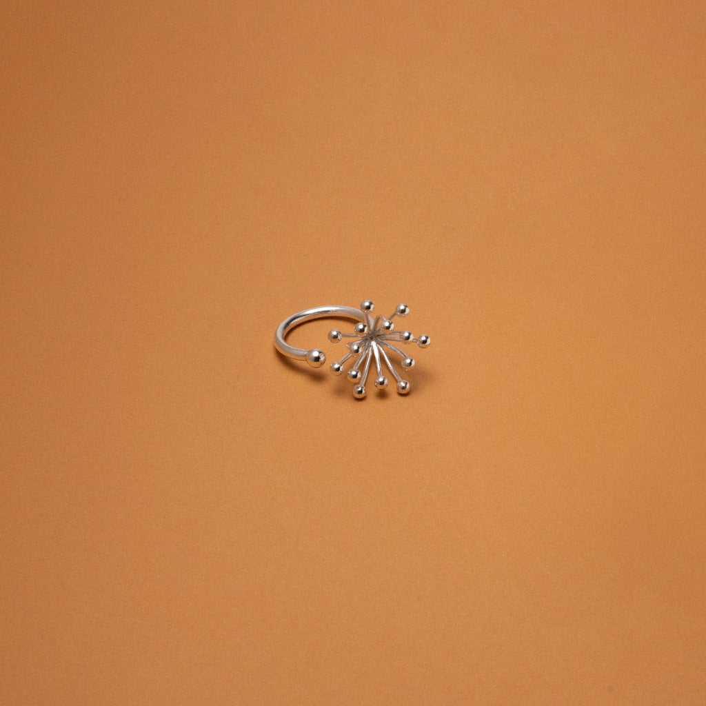 Silver ring with star-like design on an orange background