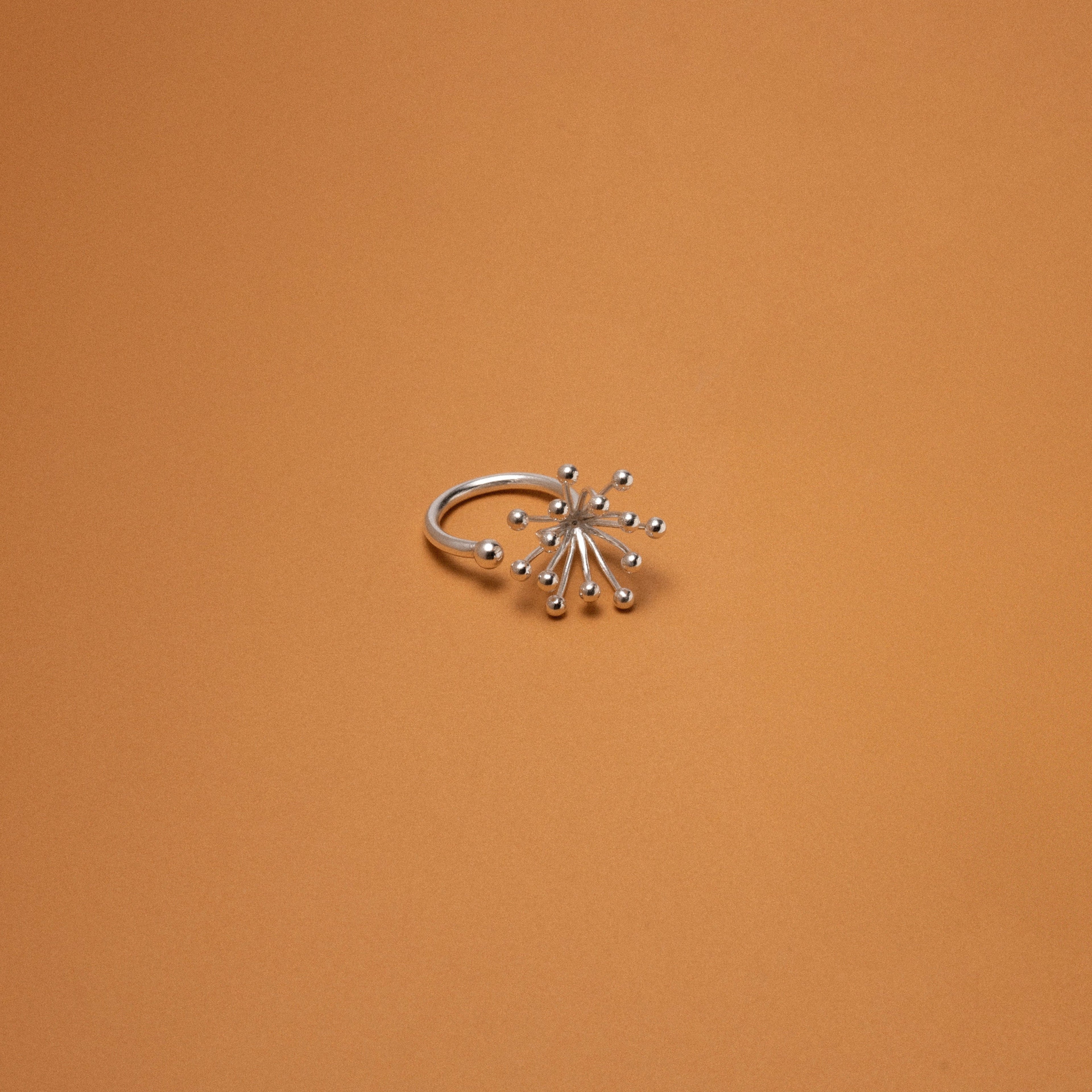 Silver ring with star-like design on an orange background